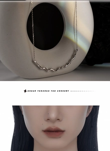 Irregular textured silver necklace on a white stand with rainbow light highlights