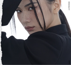 Détail artistique d'une veste noire structurée avec épaulettes et tissu texturé