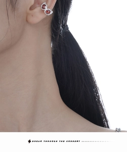 Detail of silver S925 ear cuff with two red zircon stones worn on the ear bone