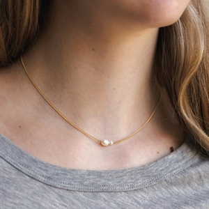 Elegant 18K gold stainless steel necklace with two staggered pearls on a female model