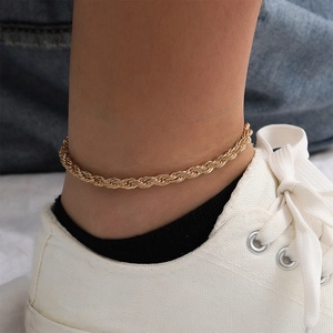 Close-up of a stylish gold rope chain anklet featuring a twisted metal texture and glossy finish