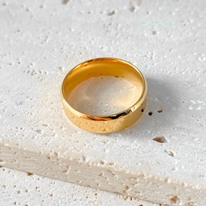 Anello ovale in acciaio inossidabile dorato lucido su pietra di travertino beige
