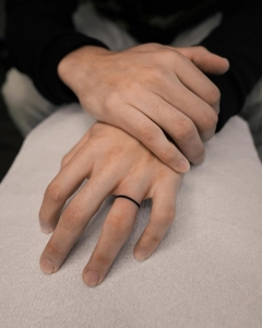 Close-up of minimalist slim black ring on male hand with matte finish details