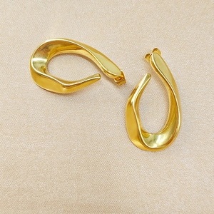 Détail des boucles d'oreilles géométriques dorées sur un fond en soie élégant
