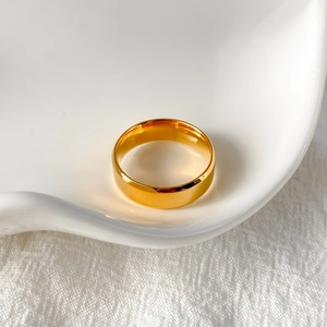 Primo piano di un anello minimalista in acciaio inossidabile dorato lucido su vassoio
