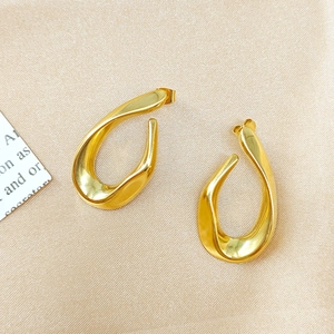 Boucles d'oreilles créoles irrégulières torsadées en acier doré sur fond de satin chic