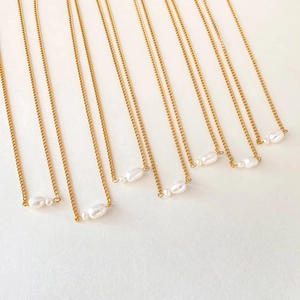 Detailed view of multiple gold stainless steel chains with elegant baroque pearl pendants