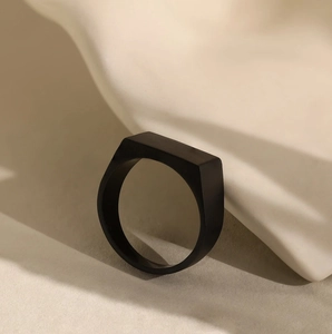 Minimalist rectangular matte black stainless steel signet ring for men on a textured surface
