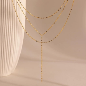 Detail of 14K gold-plated multi-layer layered necklace on a white ceramic vase