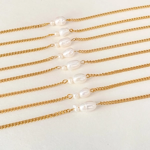 Detailed macro view of gold stainless steel Cuban chains with white baroque pearls