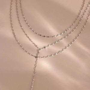 Three-layer silver stainless steel necklace with marquise links on ivory background