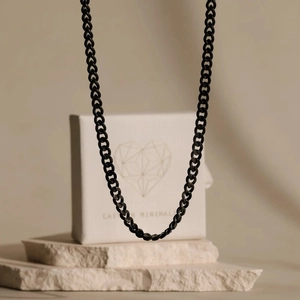 Primo piano di una catena cubana nera lucida sopra una scatola regalo minimalista