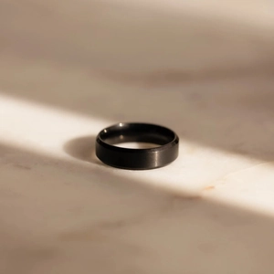 Dettaglio dell'anello in acciaio inossidabile nero opaco con finitura spazzolata su marmo