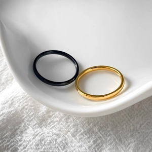 Minimalist 2mm stainless steel rings in black and gold finish on a ceramic dish