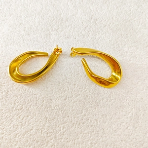 Vue macro des boucles d'oreilles géométriques dorées avec un design ovale fluide