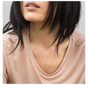 Detail shot of a hammered gold round pendant necklace worn on a neck for styling
