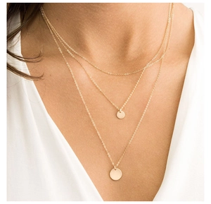 Collana a tre strati in acciaio dorato con pendenti a moneta tonda su modella