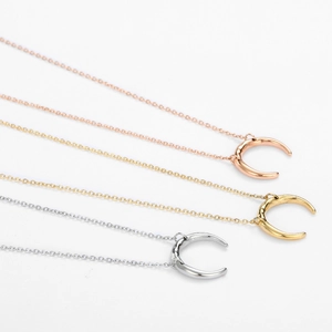 Close-up of crescent moon pendant necklaces in gold, silver, and rose gold finishes