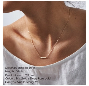 Macro detail of rectangle bar pendant necklace in gold finish on stainless steel chain