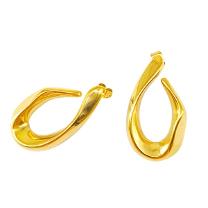 Détail macro de boucles d'oreilles dorées torsadées creuses au fini métallique poli