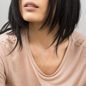 Minimalist gold stainless steel round hollow pendant necklace worn by a female model