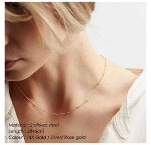 Close-up of minimalist 14K gold stainless steel bead chain necklace worn by a model