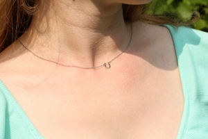 Close-up of minimalist silver U-shaped horseshoe pendant necklace worn by a model