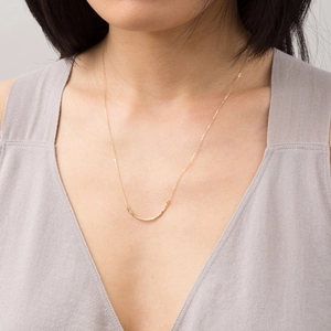 Collana minimalista con barra curva in oro 18K su collo femminile per eleganza quotidiana