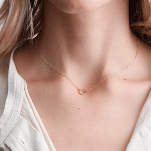 Close-up of a minimalist rose gold round ring necklace on a female model neck