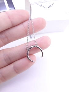 Detailed close-up of a silver crescent moon pendant with unique hammered texture surface