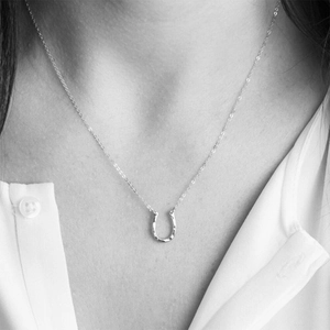 Macro shot of a silver U-shaped hammered texture pendant necklace on a neck