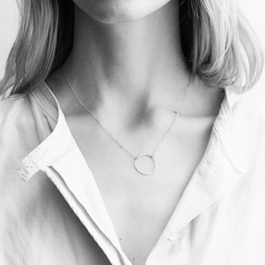 Black and white portrait of a minimalist silver hammered ring pendant necklace