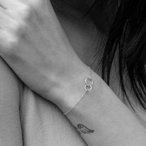 Artistic monochrome close-up of a minimalist silver double-circle bracelet on wrist