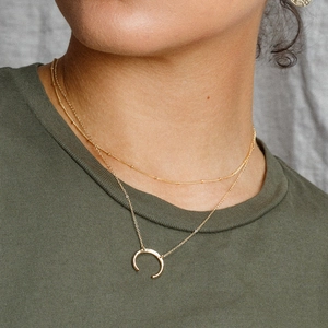 Double-layered gold necklace featuring a crescent moon pendant and satellite chain