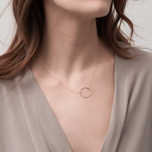 Detailed view of rose gold round pendant necklace with hammered texture on a female model