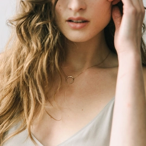 Close-up of a gold-plated moon crescent pendant necklace worn on a female model