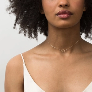Minimalist gold circle pendant necklace on a model wearing white silk clothing