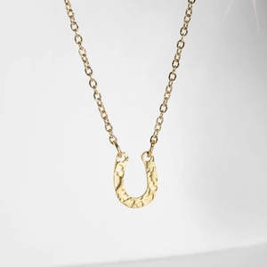 Detail showing the hammered texture on a gold U-shaped pendant with a thin O-chain