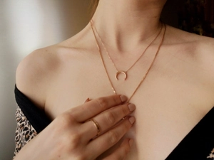 Detail of rose gold double layer crescent necklace and minimalist ring on model