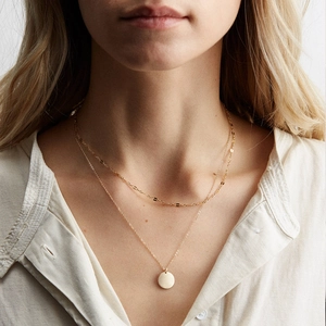 Collana a due strati in acciaio inossidabile dorato con ciondolo a moneta su una modella