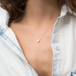 Close-up of minimalist rose gold round pendant necklace worn on a female model