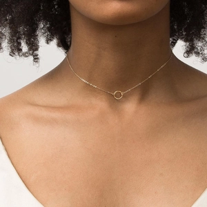 Close-up of minimalist gold plated stainless steel necklace with hammered circle pendant