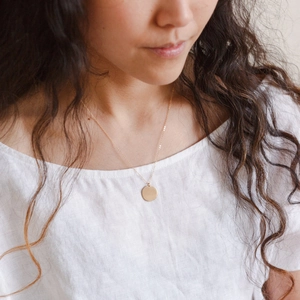 Gros plan d'un collier à pendentif rond plaqué or minimaliste sur un mannequin