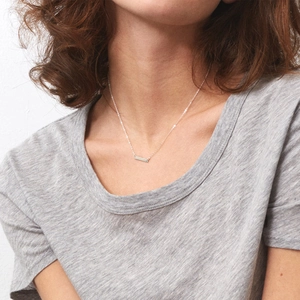Minimalist silver bar pendant necklace on a delicate chain worn by a female model