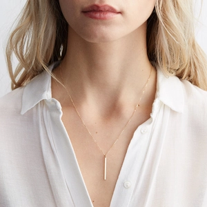 Minimalist gold bar pendant necklace on female model with delicate O-chain link