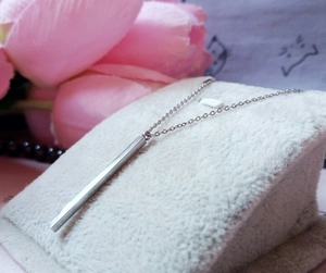 Detailed view of a silver stainless steel vertical bar pendant on a delicate link chain