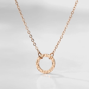 Macro view of rose gold hammered circle pendant necklace with detailed metal texture