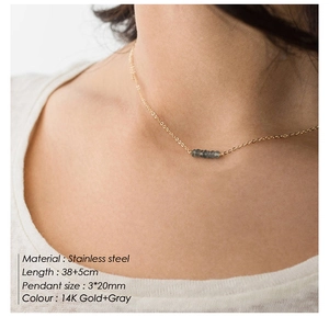 Détail d'un collier en acier doré 14K avec pendentif en pierre grise sur un mannequin
