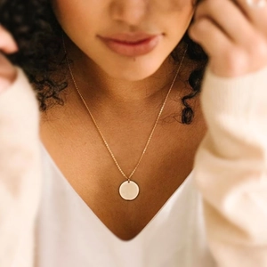 Collier en acier inoxydable doré avec pendentif rond sur le cou d'un modèle
