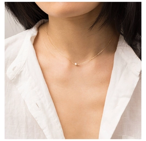 Pendentif perle d'eau douce minimaliste sur fine chaîne dorée portée sur le clavicule